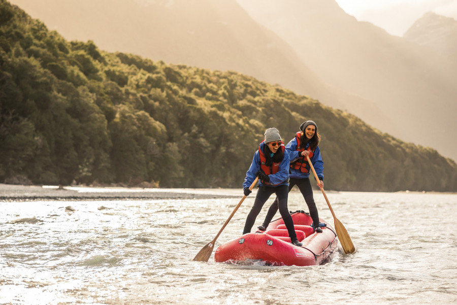 Two ladies standing on inflatable kayak laughing 